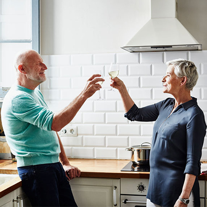 two mature adults toasting in kitchen